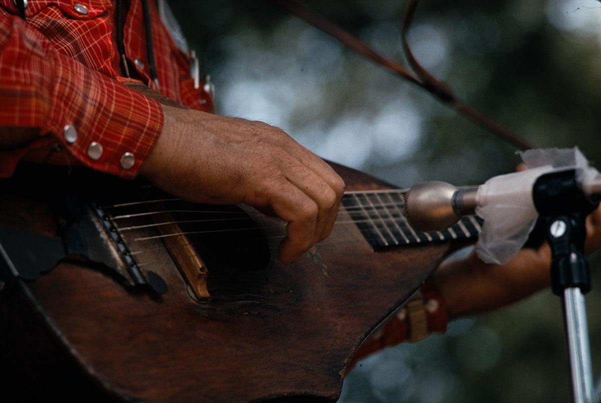 A close shot of a hand strumming a wooden string instrument.